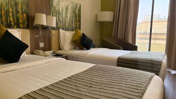 Quarto de hotel com duas camas, uma janela grande e um quadro na parede.