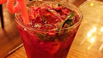 A glass with a red beverage, ice, and a straw.