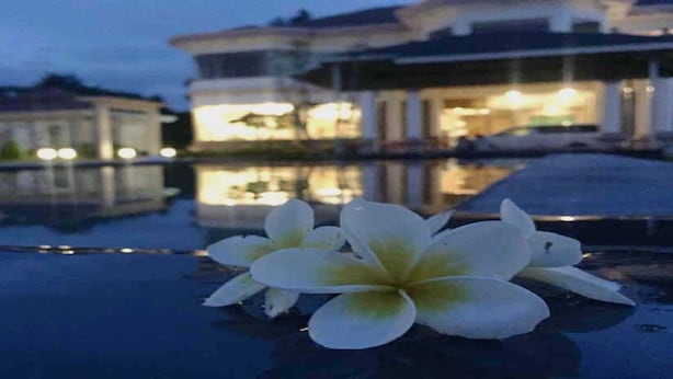 A white flower on a reflective surface near a body of water with buildings in the background. - Ativara Hotels And Resorts (Nyaungshwe)