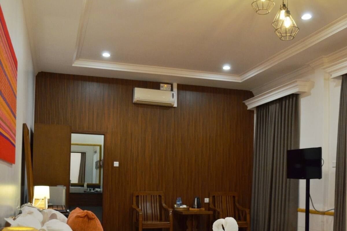 A hotel room with a large bed, a desk with a chair, a TV, and a lamp.