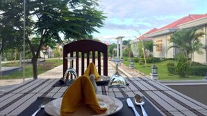 A table set outdoors with a chair, a plate with a folded napkin, and a glass. - Ativara Hotels And Resorts (Nyaungshwe)