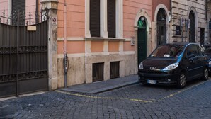 A pink building with a black car parked in front. - Maison Brunetti (Rome)