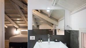 A modern bathroom with a large white sink, a mirror, and a dark tiled backsplash. - Maison Brunetti (Rome)