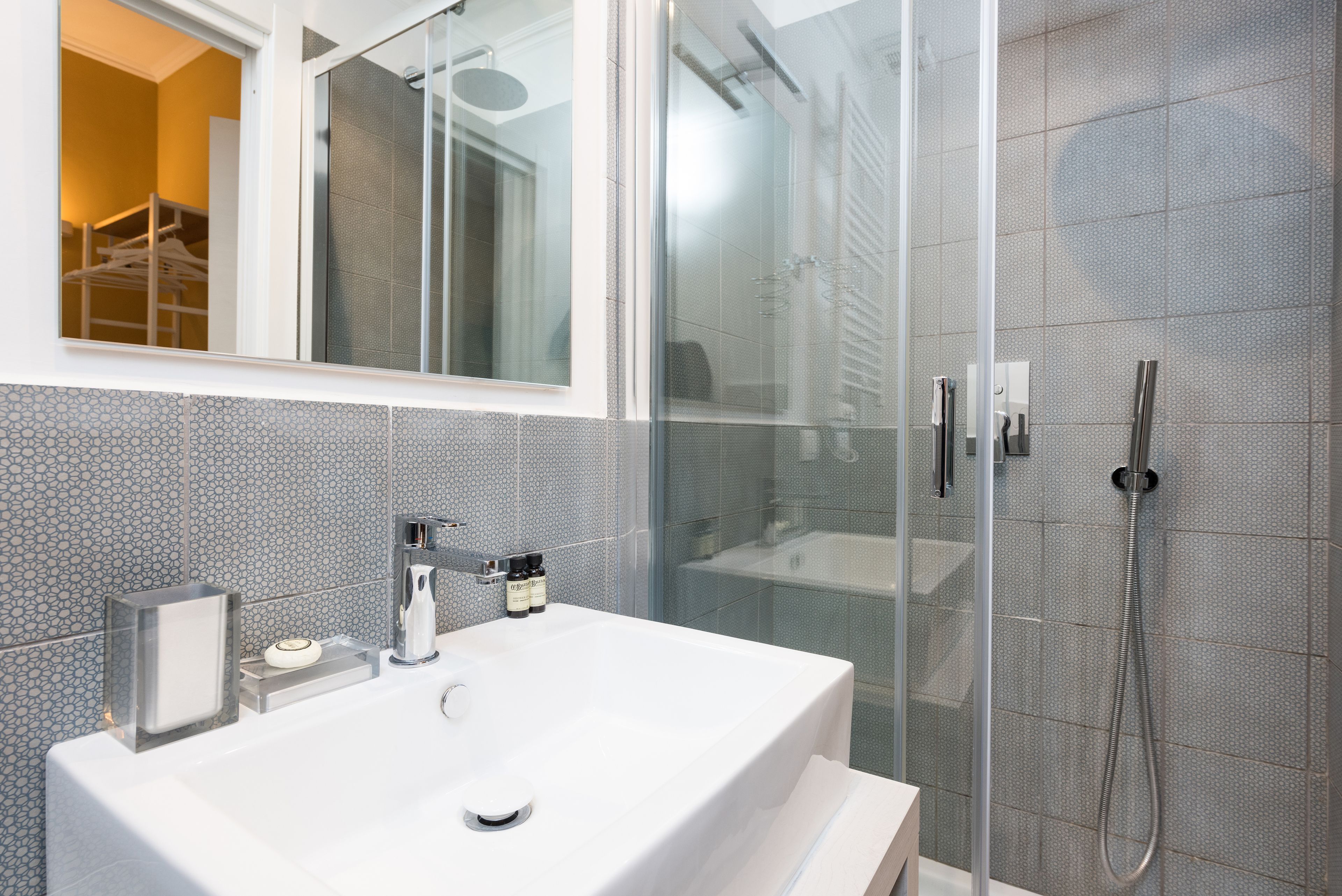 A modern bathroom with a large white sink, a glass shower enclosure, and a mirror above the sink.