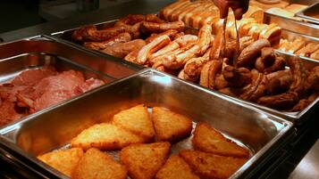 A buffet with various food items including sausages, pastries, and fried items.