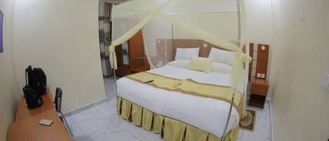 Una habitación de hotel con cama, mesita de noche, silla y escritorio.