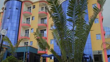 Un hôtel à plusieurs étages doté de balcons, d’une façade en verre bleue et d’une façade extérieure jaune et rouge.