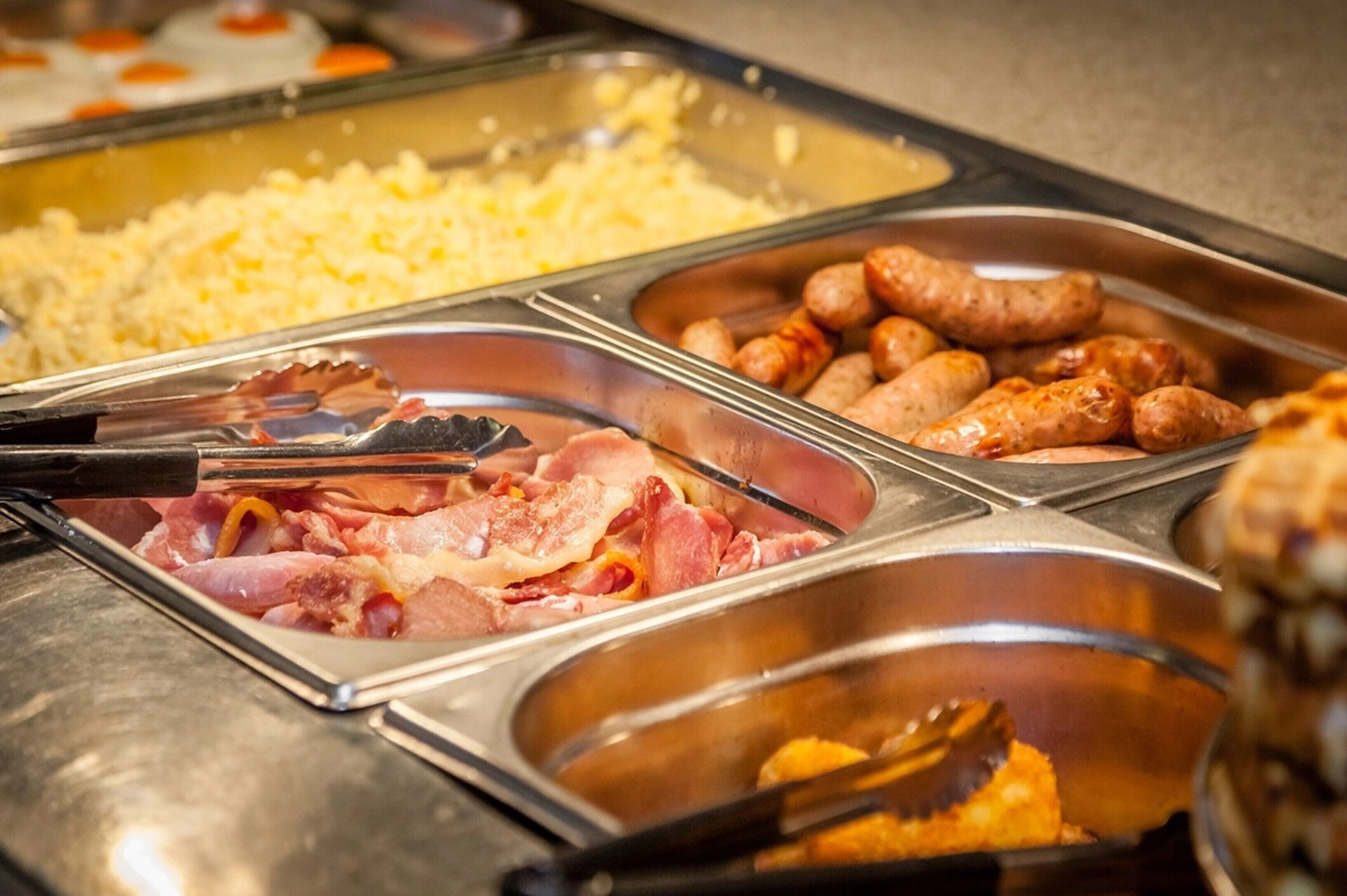 A buffet with various food items including sausages, cheese, and bacon.