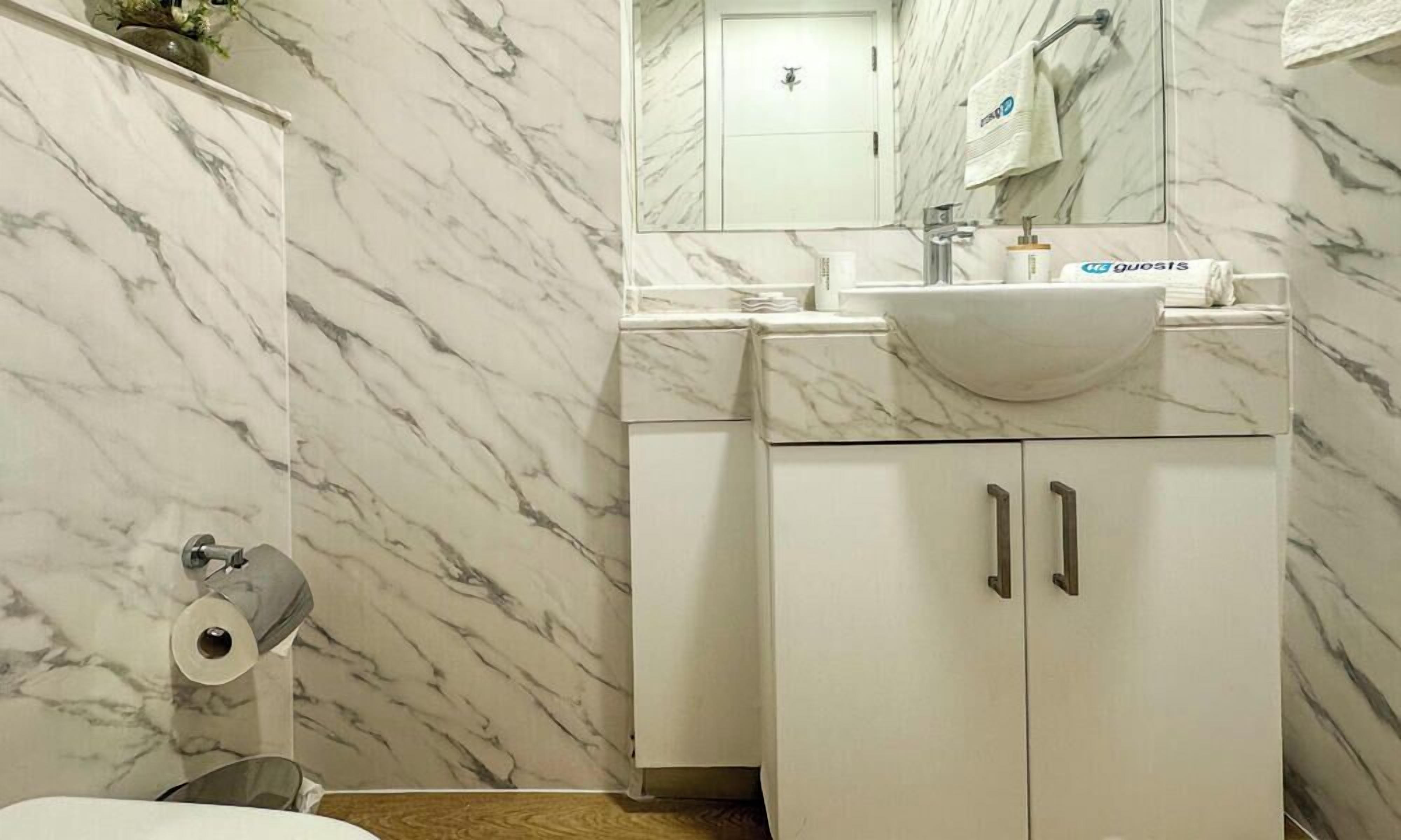 Une salle de bain avec un mur en marbre, un lavabo et des toilettes.