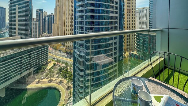 Un immeuble de grande hauteur doté d’un balcon en verre qui offre une vue sur le paysage urbain.