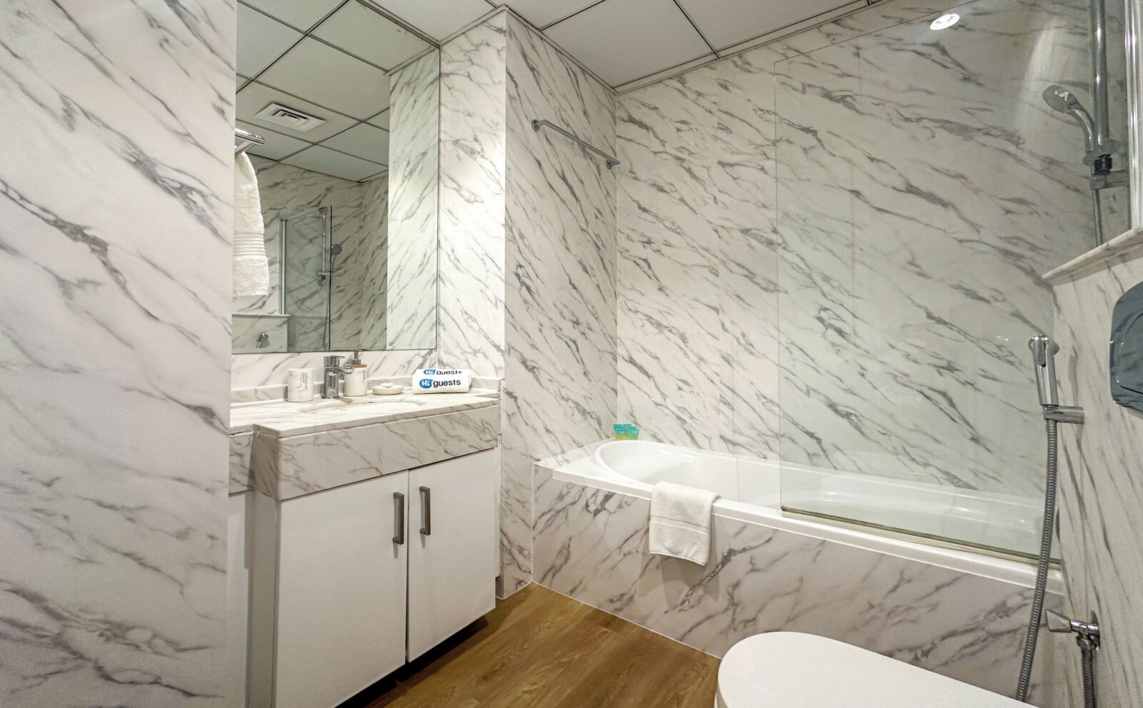 Ein Badezimmer mit Marmorwänden, einem weißen Waschbecken und einer Dusche.