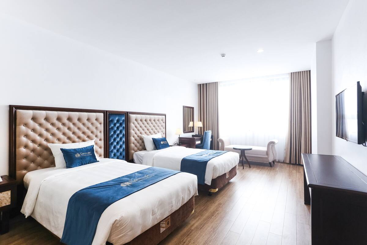Une chambre d’hôtel avec deux lits, un bureau, une chaise et un téléviseur.