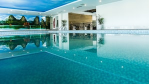 A large indoor swimming pool with a clear blue water surface, surrounded by a tiled deck. - Song Loc Luxury (Bai Chay)