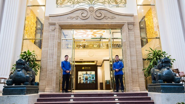 A grand entrance with two men standing in front, flanked by statues of lions. - Song Loc Luxury (Bai Chay)