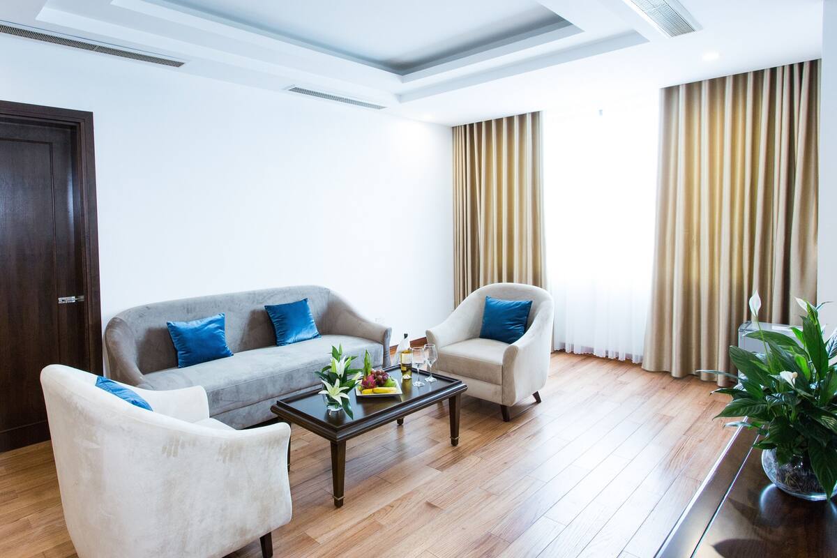 Un salon moderne avec un canapé gris, un fauteuil blanc et une table basse en bois.