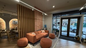 A modern interior with a sofa set, ottomans, a patterned rug, and a view through a glass door. - Bugu Hotel (Bishkek)