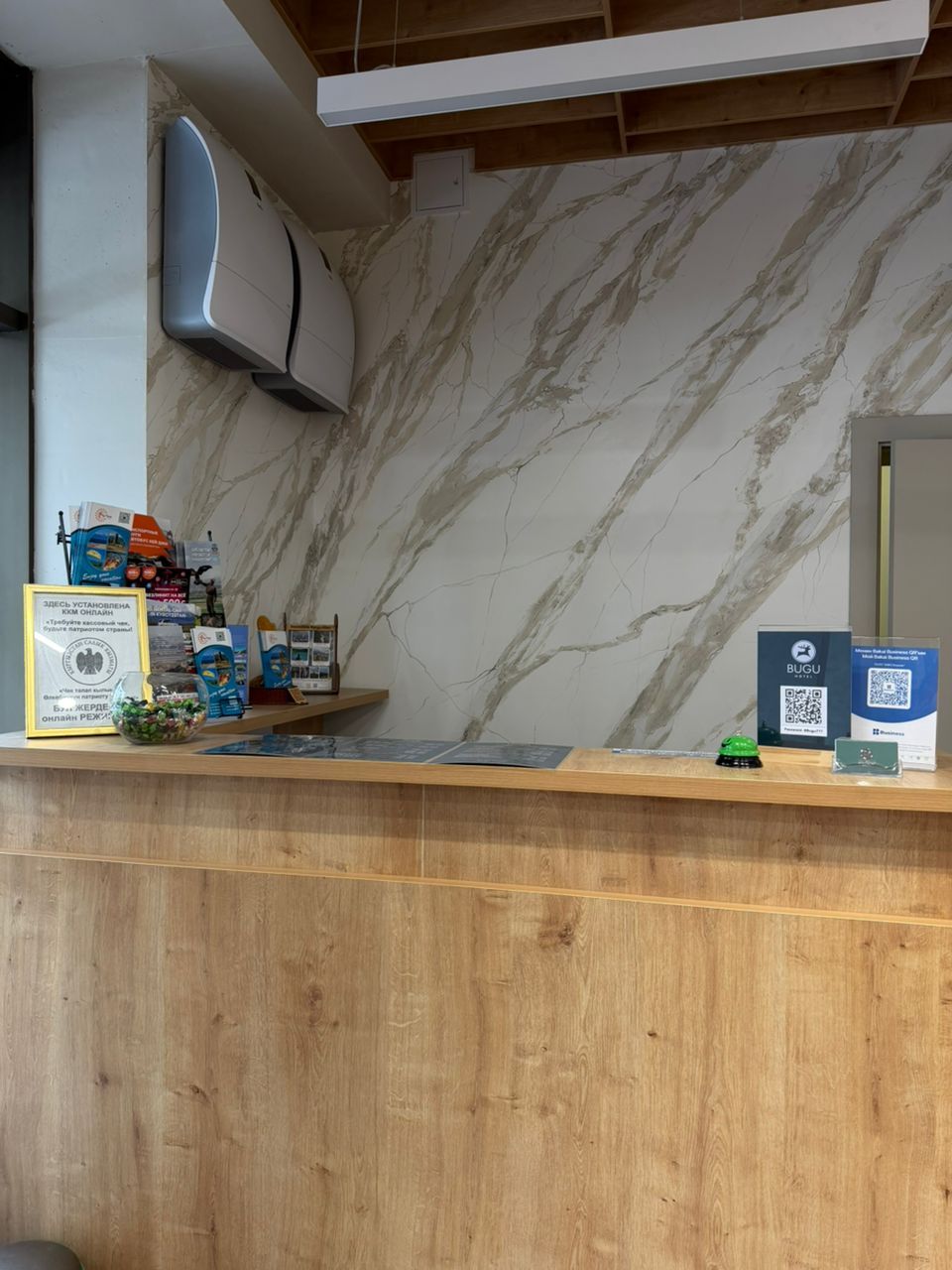 A reception desk with a marble wall, a mounted air conditioner, and various informational signs.