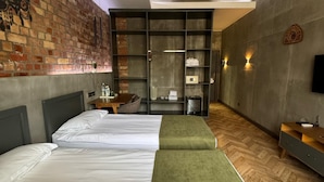 A modern hotel room with two beds, a brick accent wall, a built-in wardrobe, and a television. - Bugu Hotel (Bishkek)