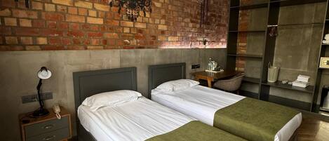 Une chambre d’hôtel avec deux lits, un mur en briques, un lustre et une armoire avec des étagères.