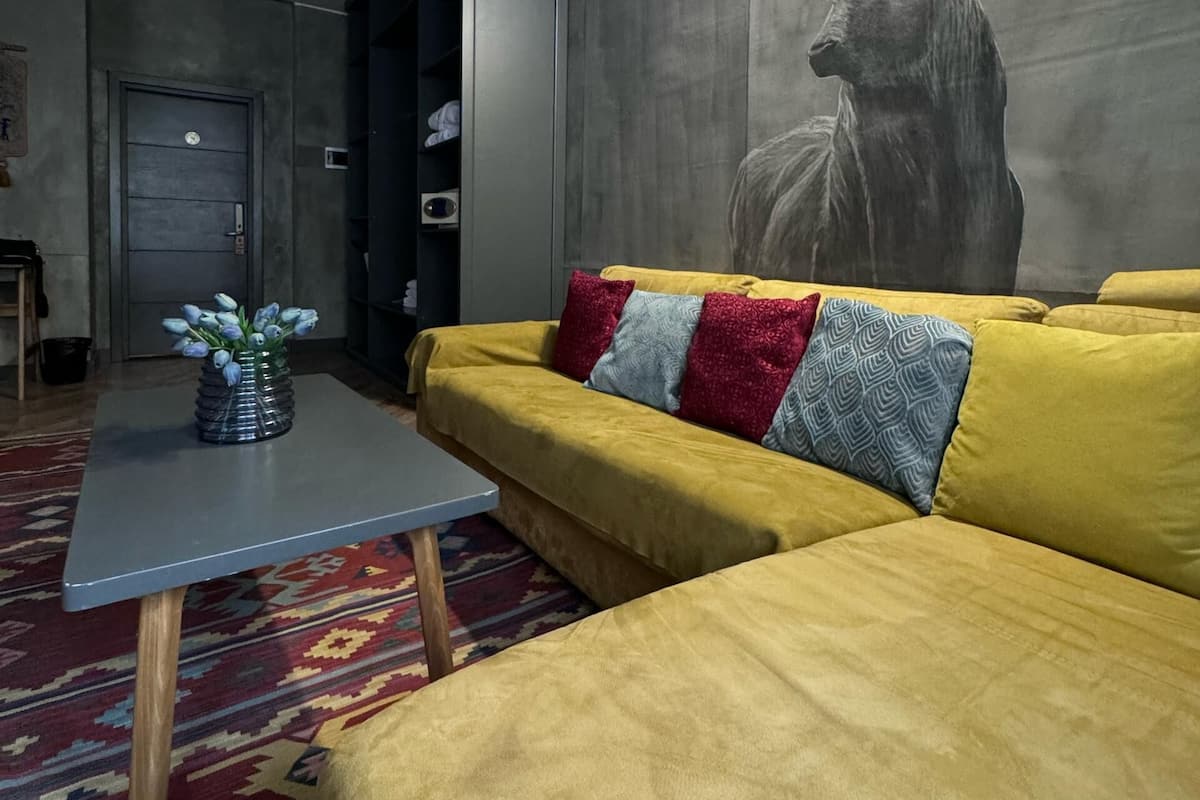 Una sala de estar moderna con un sofá amarillo, un tapete estampado y una escultura de ciervo montada en la pared.
