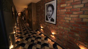 A hallway with a checkered floor, brick walls, and framed pictures. - Bugu Hotel (Bishkek)