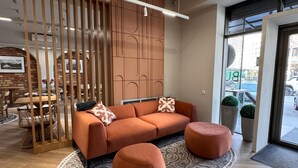 A modern living area with a sofa, ottomans, and a patterned rug. - Bugu Hotel (Bishkek)