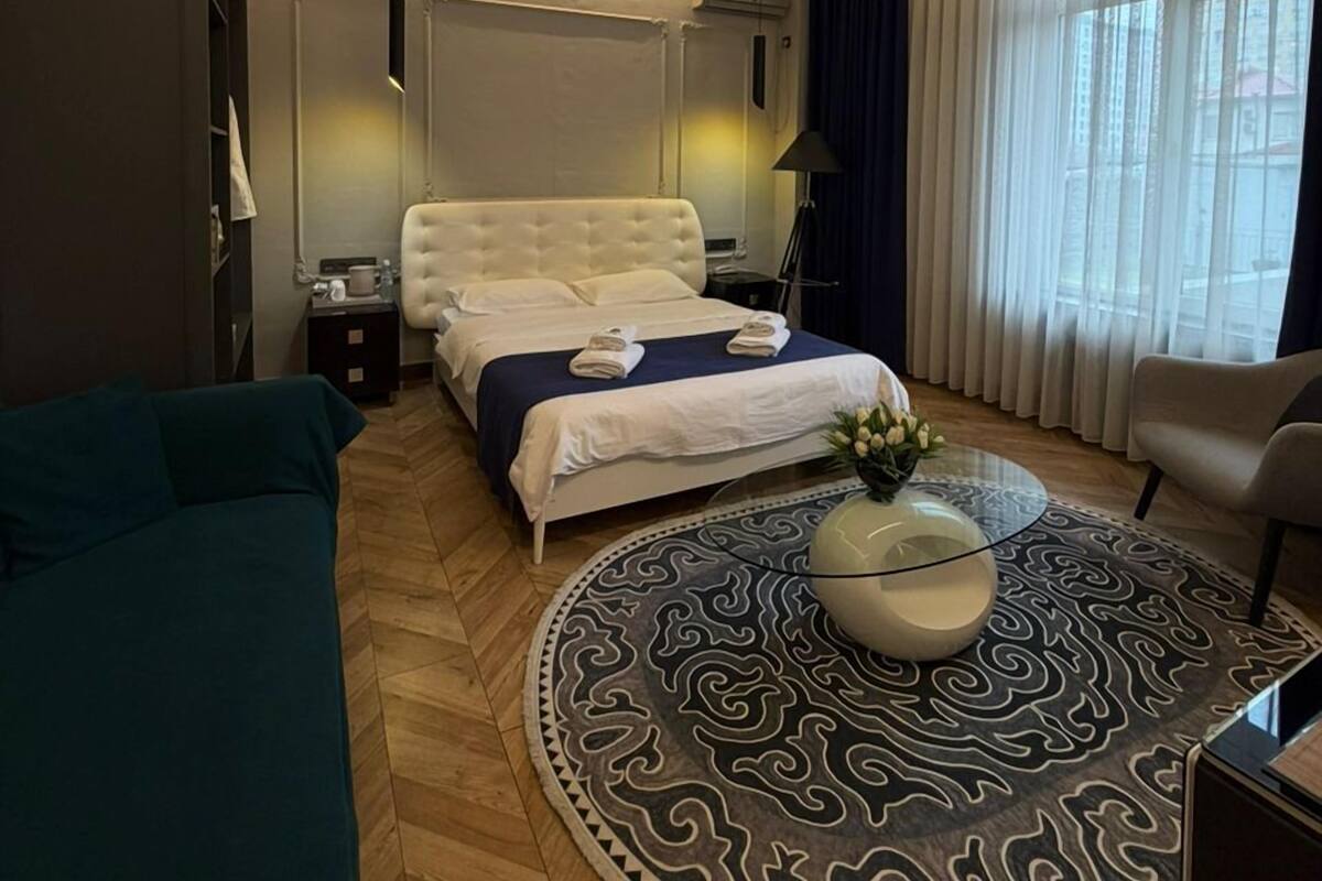 Una habitación de hotel moderna con una cama, una mesita de centro redonda, un sofá y una silla.