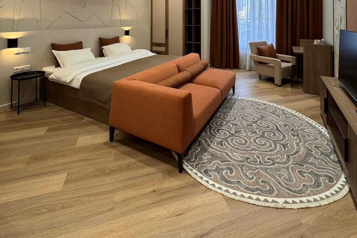 Una habitación de hotel moderna con una cama grande, un sofá, un televisor y una pequeña mesa.