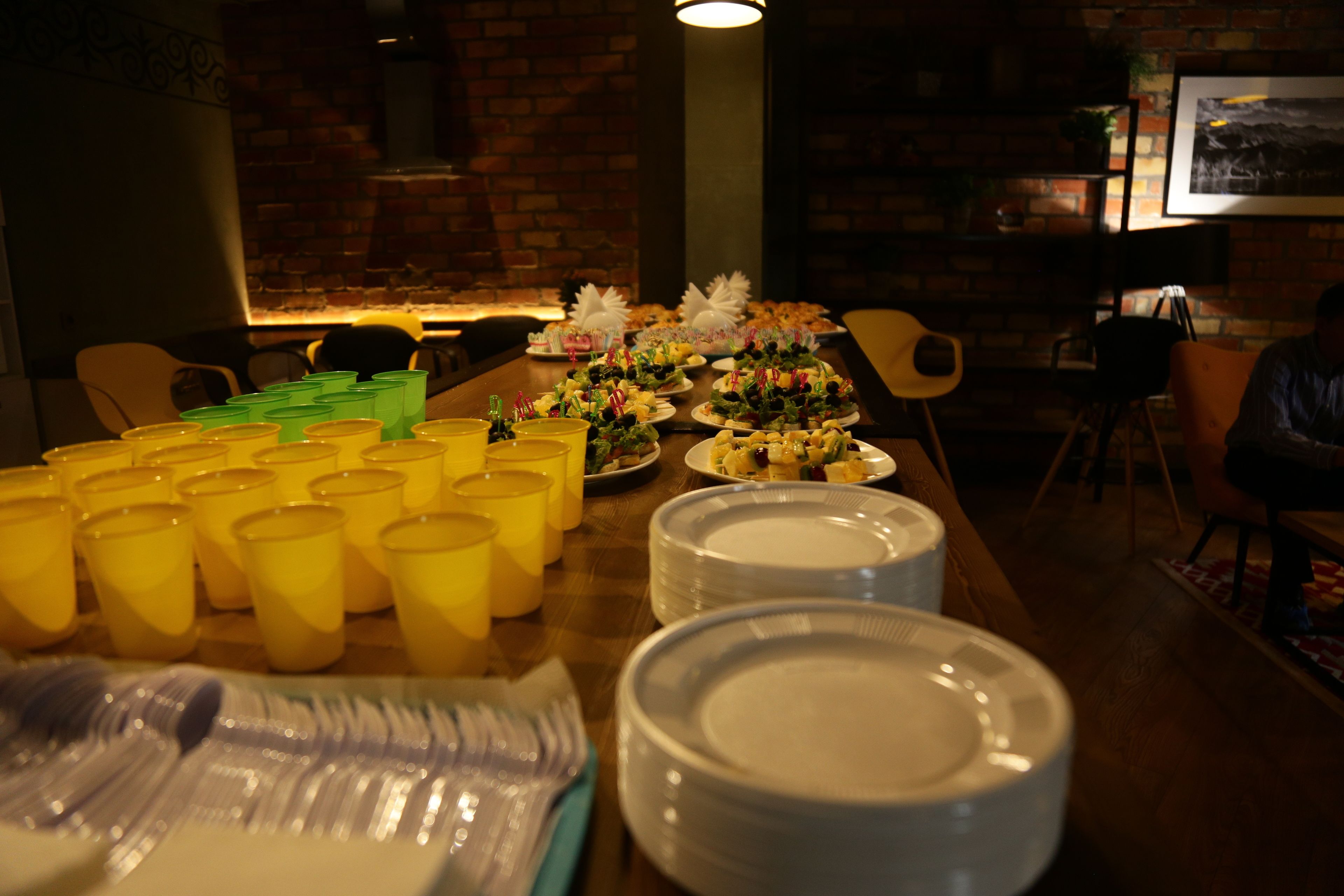 A dining table set with yellow cups, plates, and a variety of food items.