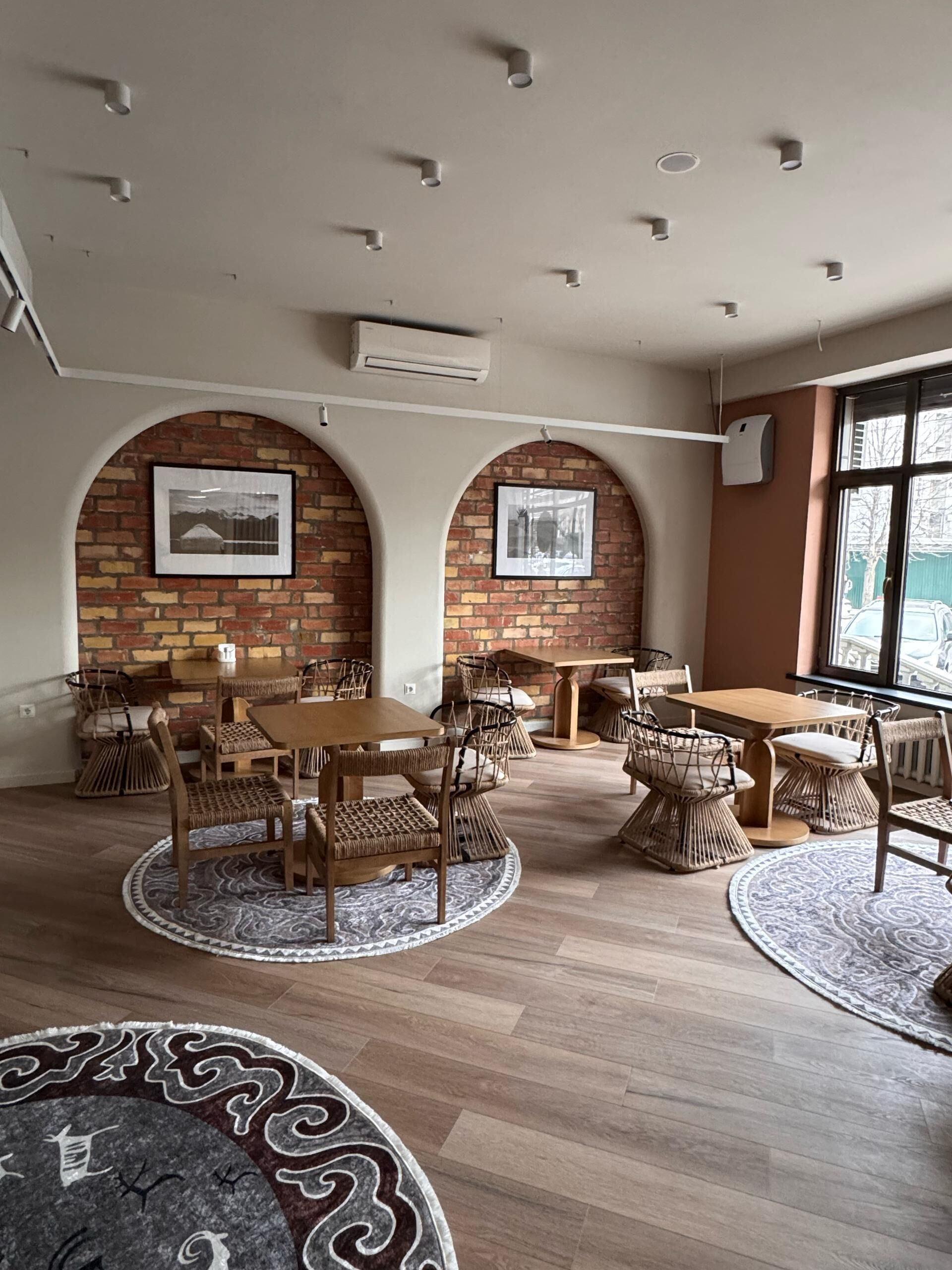 A modern interior with brick walls, wooden tables, and wicker chairs.