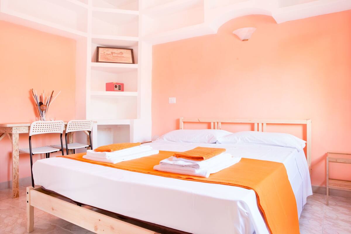 A bedroom with a bed, a desk, and chairs.