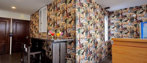 Un hall de hotel con papel tapiz estampado, una recepción y una zona de bar.