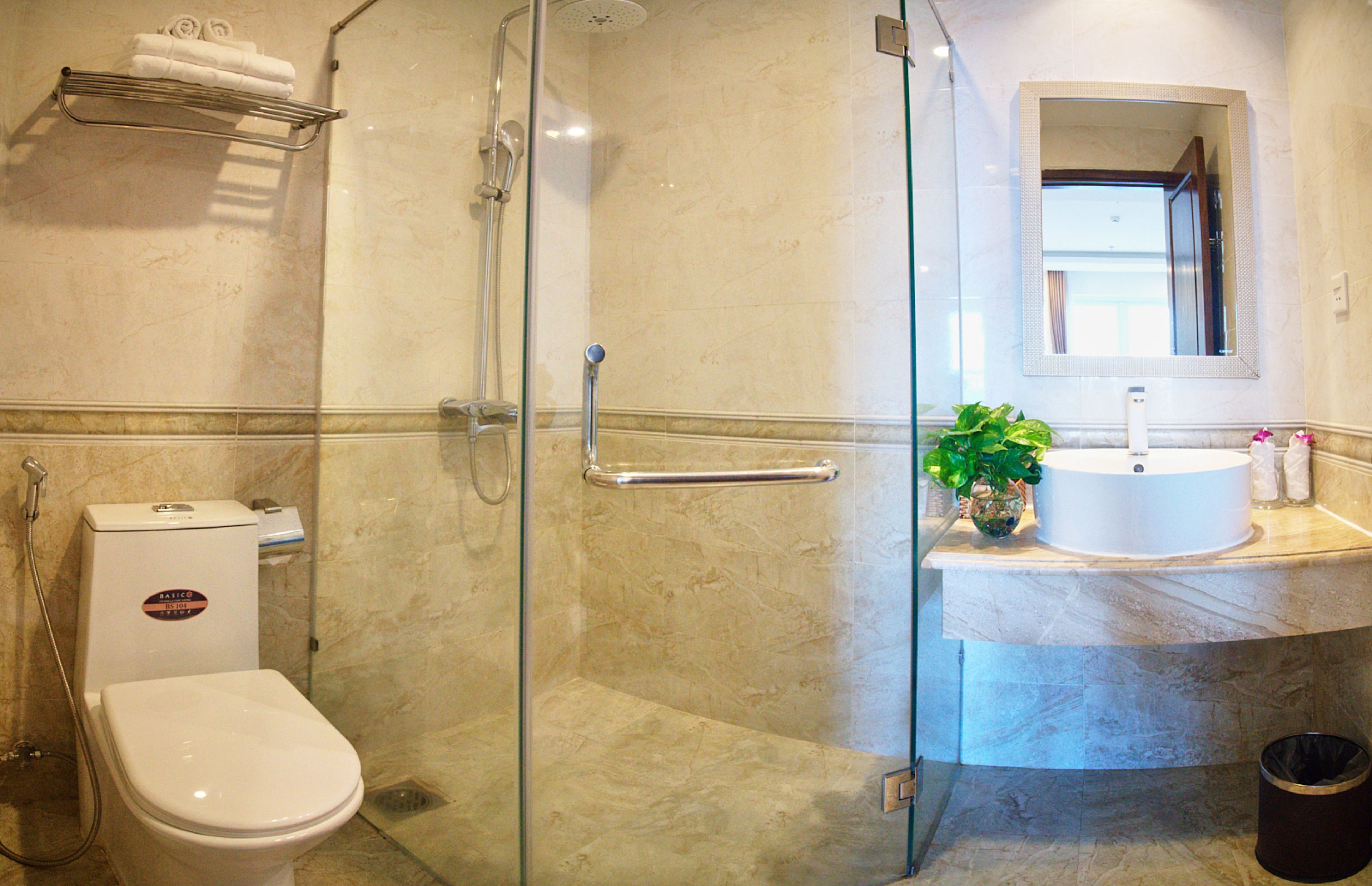A bathroom with a glass-enclosed shower, a toilet, a sink with a mirror, and a towel rack.
