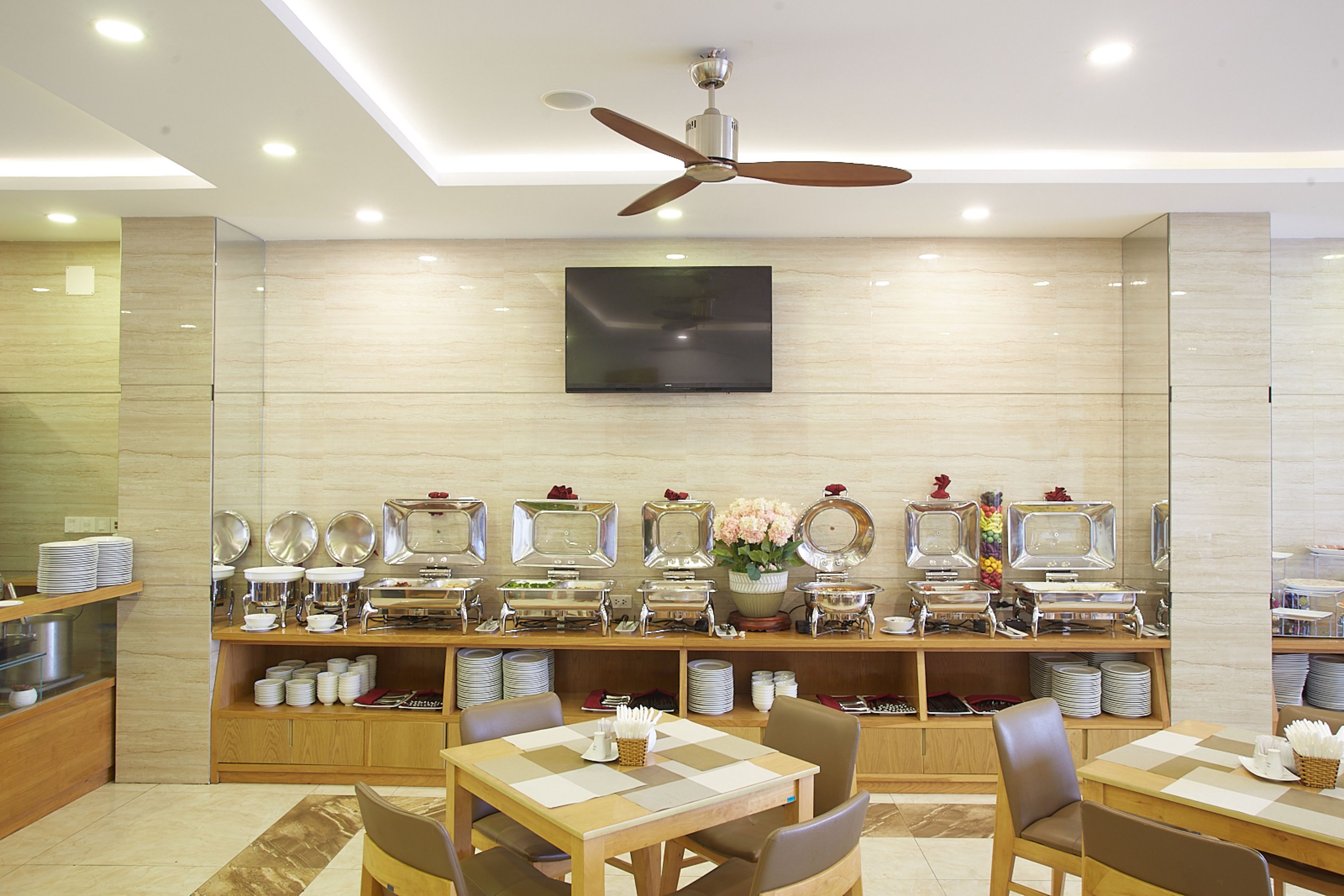 A buffet area with multiple serving stations, a ceiling fan, and a flat-screen TV mounted on the wall.