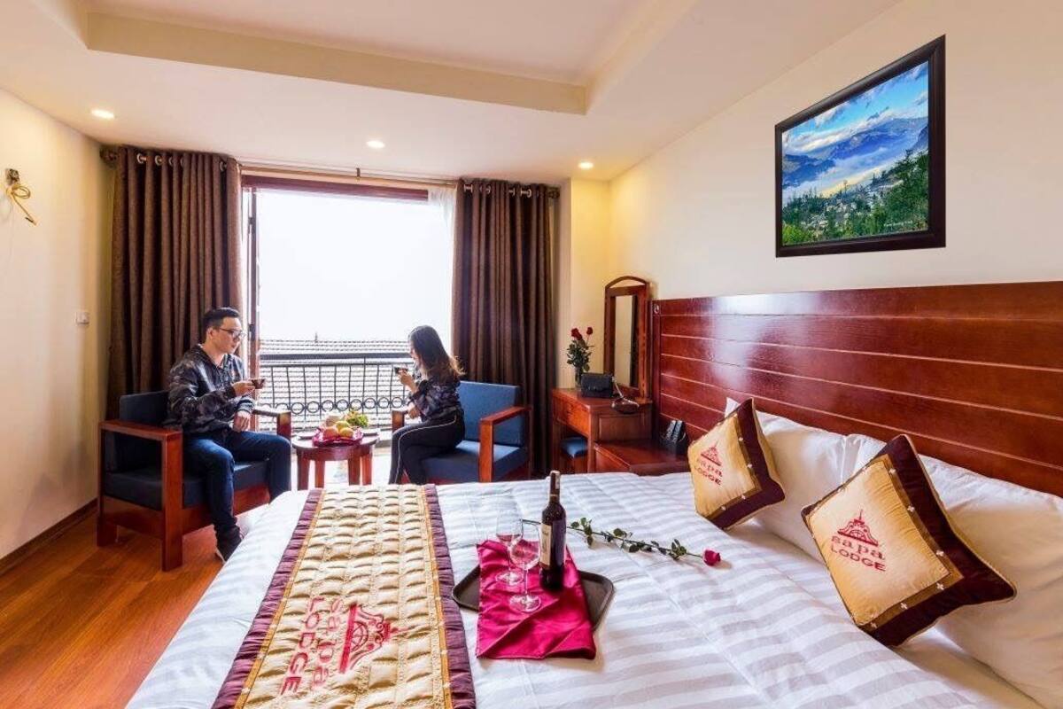 Ein Hotelzimmer mit Bett, zwei Stühlen, einem Tisch, einem Fenster und einem Bild an der Wand.