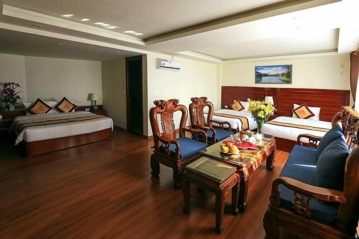 Ein Hotelzimmer mit zwei Betten, Holzmöbeln, einem Esstisch und einem Bild an der Wand.