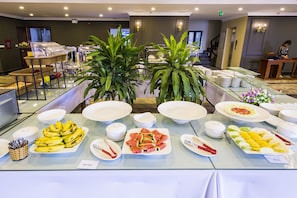 A buffet with various food items and a seating area with a person.