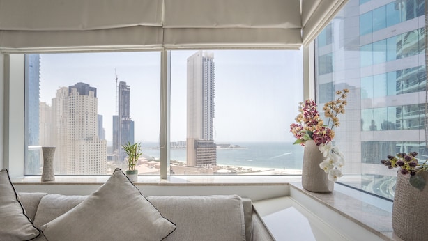 Una sala de estar moderna con un amplio ventanal que ofrece vistas a la ciudad y al mar.