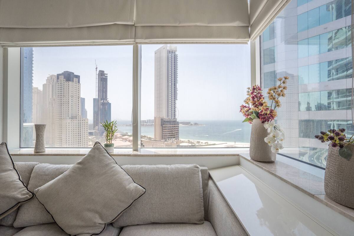 Una sala de estar moderna con un amplio ventanal que ofrece vistas a la ciudad y al mar.