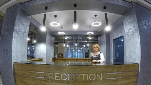 A reception area with a wooden reception desk labeled "RECEPTION," overhead circular lighting, and a view of the interior space. - Druzhba (Kyiv)