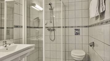 A bathroom with a glass-enclosed shower, a white sink, and a toilet.