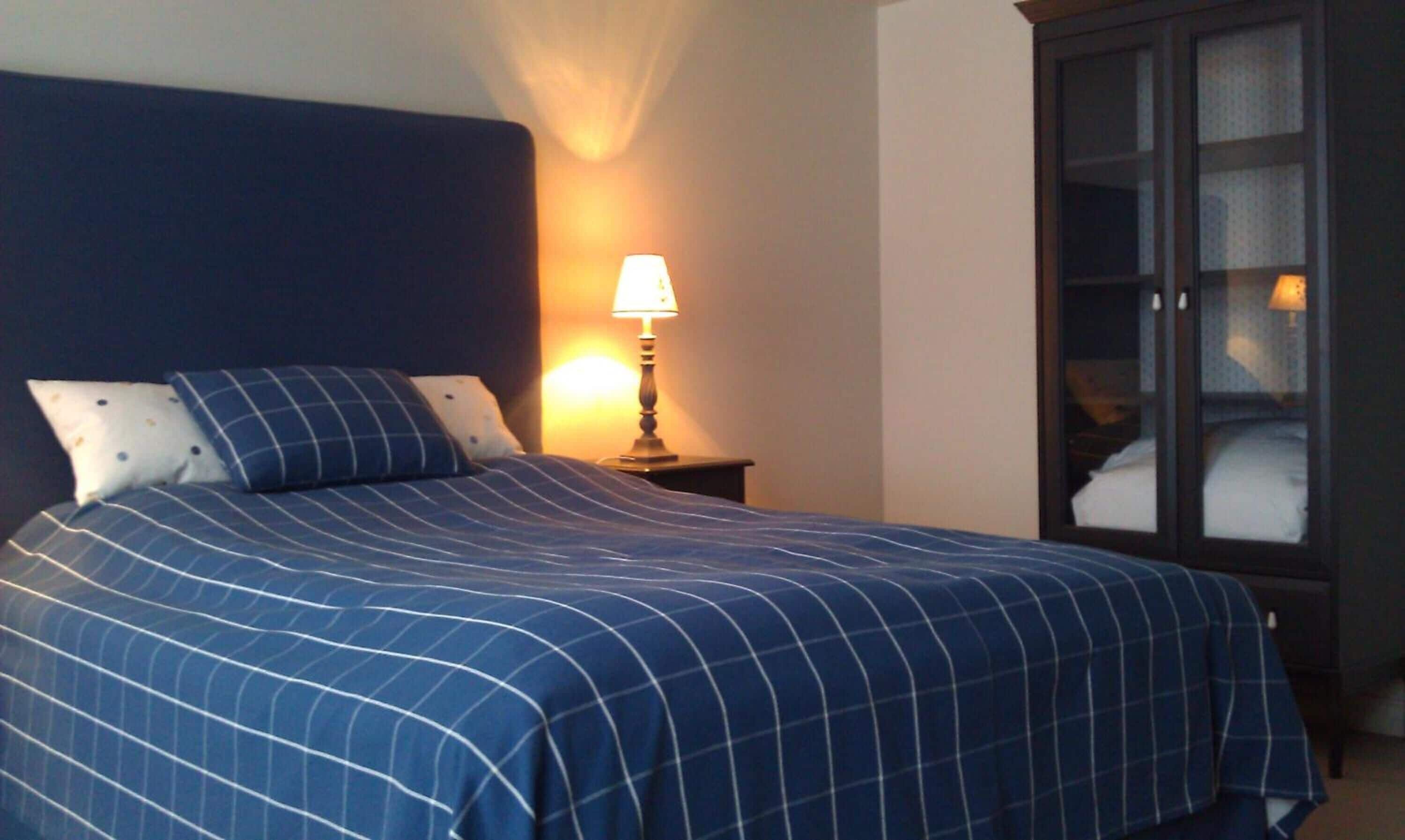 Ein Hotelzimmer mit einem großen Bett, einem Nachttisch mit Lampe und einem Kleiderschrank.