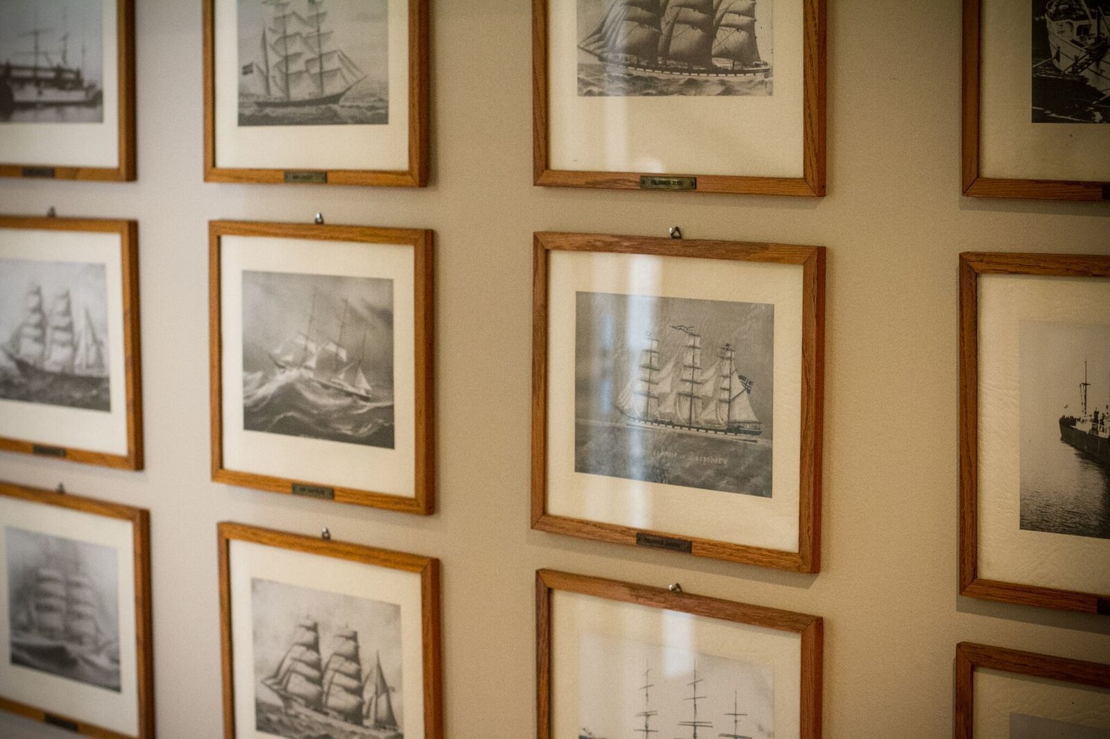 Una parete con diverse fotografie in bianco e nero di velieri.