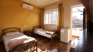 A room with two beds, a small refrigerator, and a window with curtains. - Sun Rise Hotel (Amman)