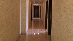 A long, narrow hallway with a tiled floor and a ceiling with recessed lighting. - Sun Rise Hotel (Amman)