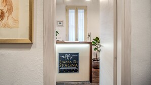 A reception desk with a sign for 'Piazza Di Spagna Comfort Rooms' and a framed artwork on the wall. - Piazza di Spagna Comfort Rooms (Rome)