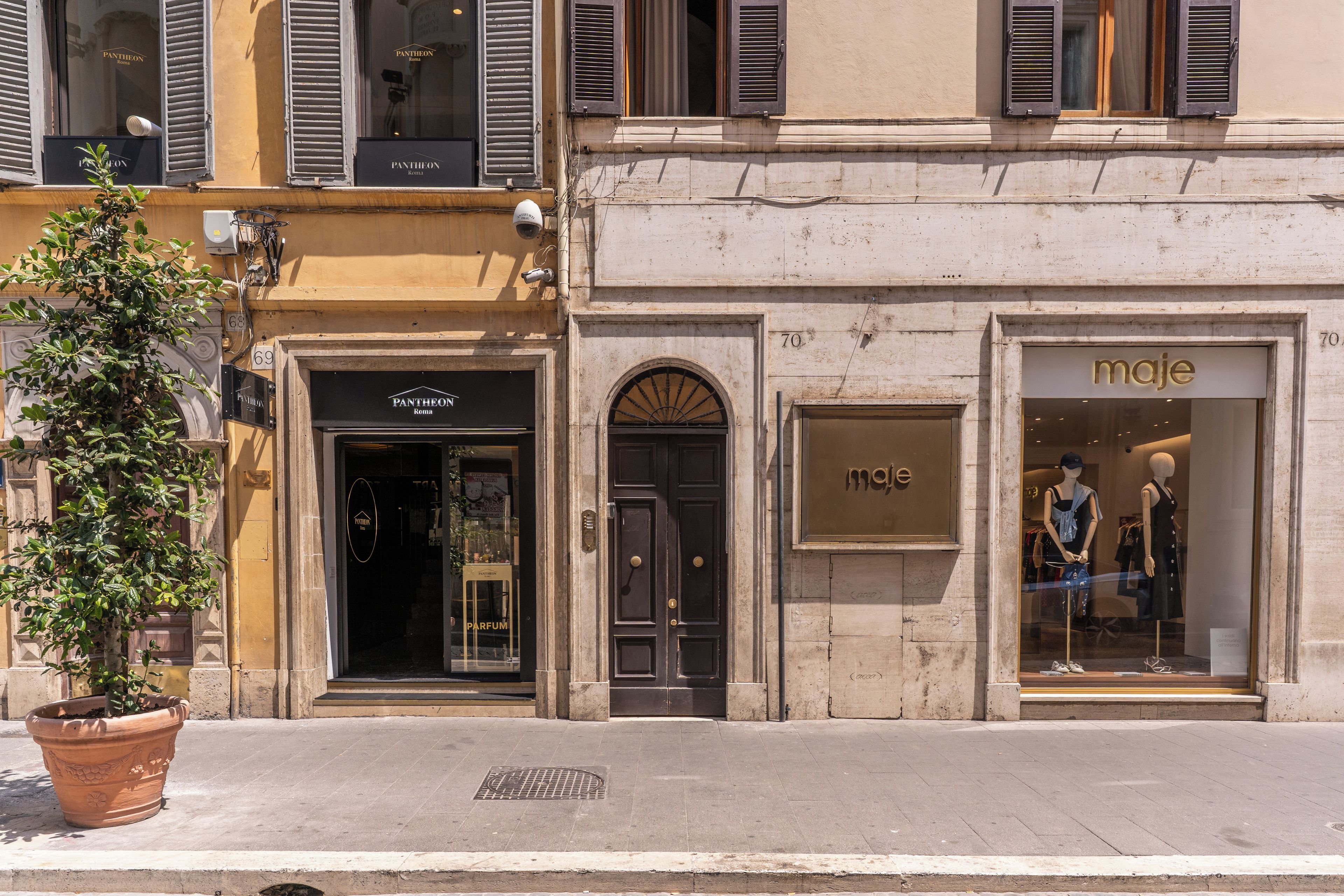 A street view with storefronts, including a Pantheon store and a maja store.