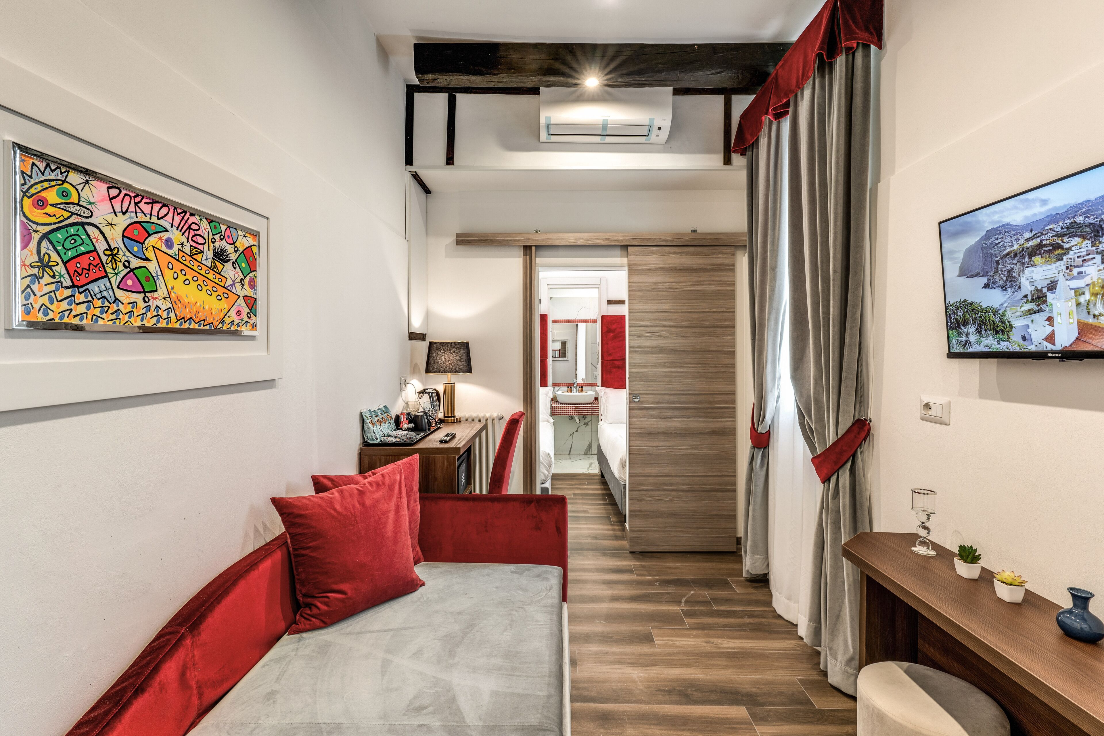 A modern hotel room with a bed, a desk, and a TV.