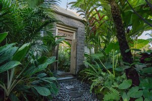 Un jardín exuberante con un sendero de piedra que lleva a una puerta de madera.