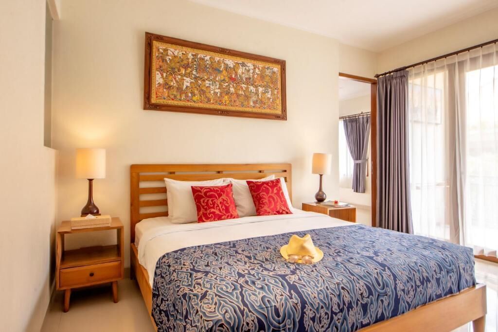 Una habitación de hotel con una cama, dos mesitas de noche, una lámpara y un cuadro colgado en la pared.